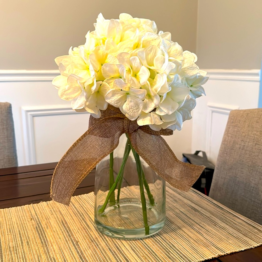 Artificial white hydrangea arrangement in glass vase.